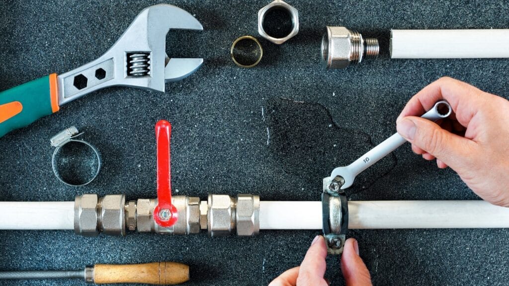 Plumber repairing a pipe valve with an adjustable wrench in DeLand