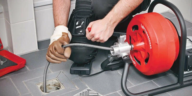 Plumber using a drain-cleaning machine in DeLand