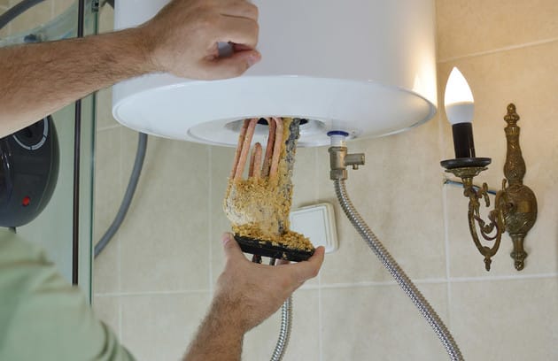 Technician removing mineral buildup from a water heater in DeLand