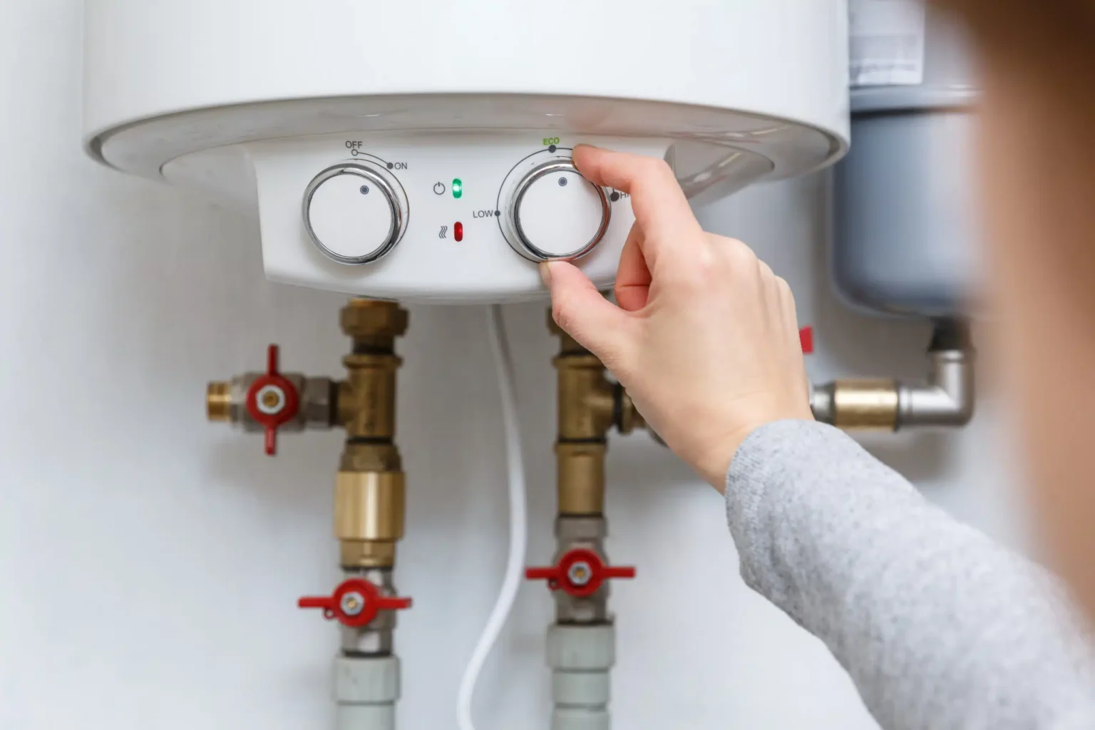 Homeowner adjusting the temperature controls on a water heater in DeLand